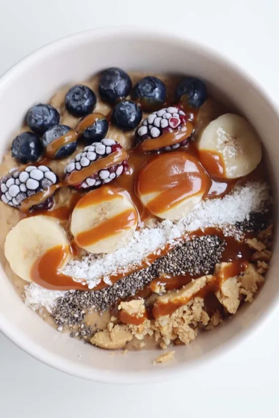 Tigela de salada de frutas com banana, coco e calda por cima