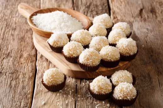Beijinhos de coco enrolados, servidos em tigela de madeira
