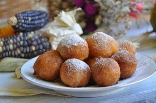 Bolinhos de chuva polvilhados com açúcar, servidos em prato branco