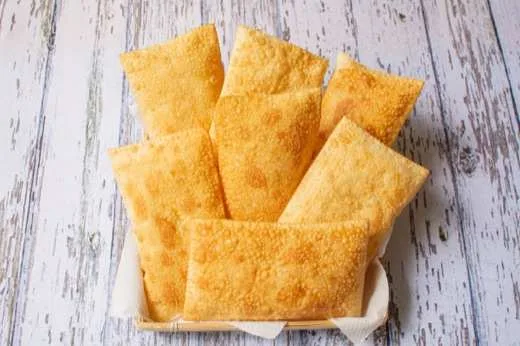 Pastéis fritos dourados servidos sobre tábua de madeira clara